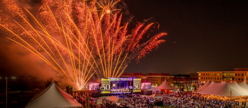 UMBC campus at nighttime while celebrating the university's 50th anniversary with a huge crowd and sky of fireworks.