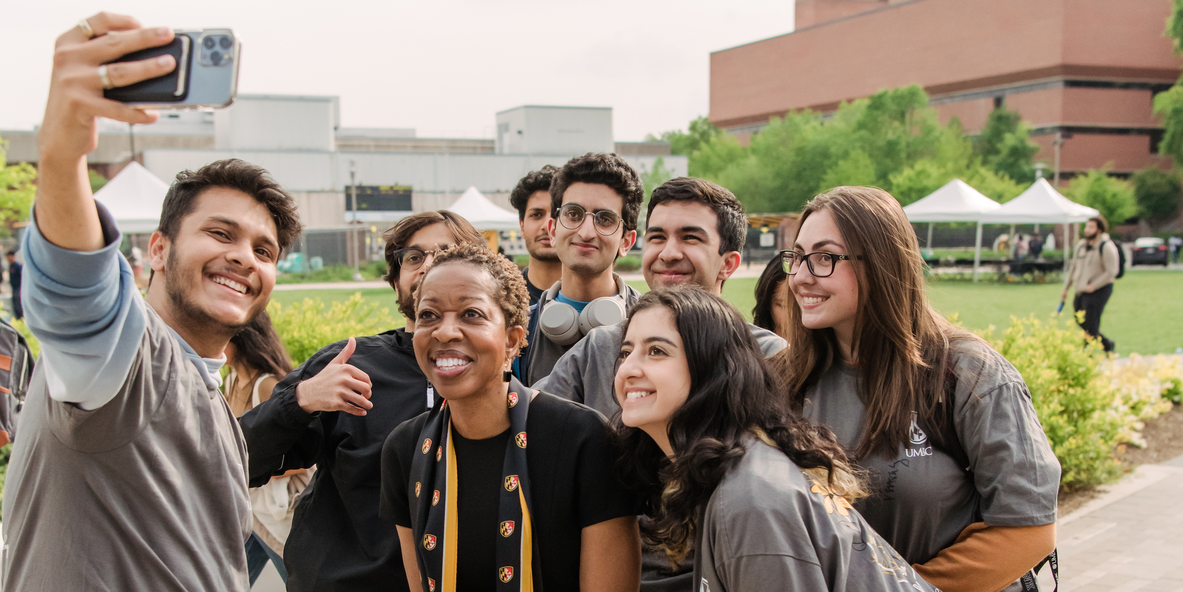 Wearing black and gold formal attire, UMBC's president Valerie Shears Ashby poses for a selfie with excited students.